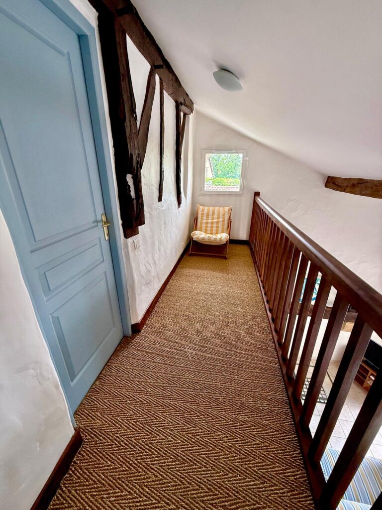 Couloir étage avec tapis en sisal et poutres anciennes - gîte Le Sau Nouvelle-Aquitaine