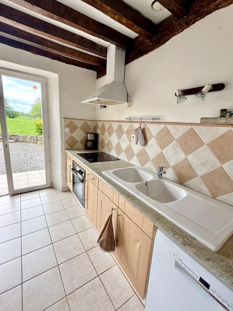 Cuisine équipée avec porte-fenêtre vue jardin - gîte Le Sau dans les Landes