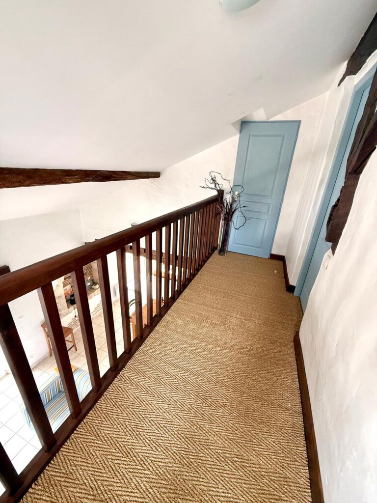 Palier de mezzanine avec portes bleues et tapis en sisal - gîte Le Sau à Peyrehorade