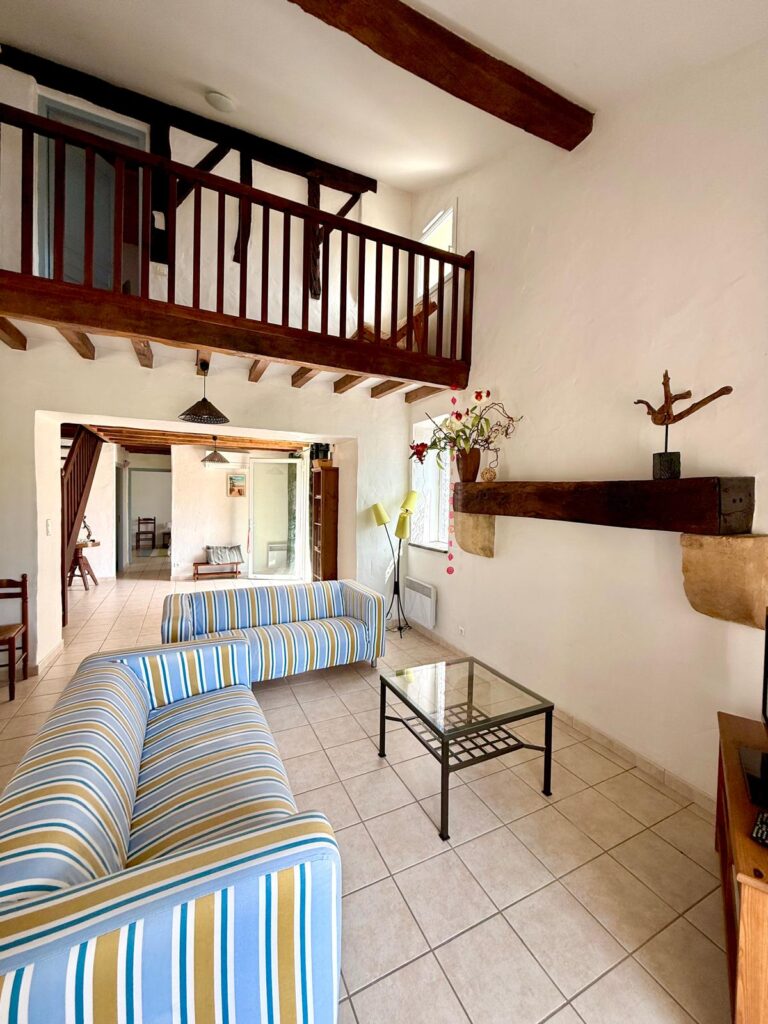 Salon convivial avec canapés rayés et mezzanine sous charpente - gîte Le Sau à Peyrehorade